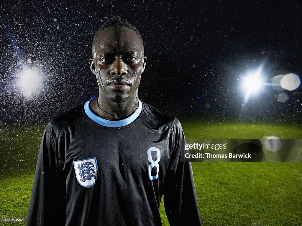 Soccer player standing on field in rainstorm