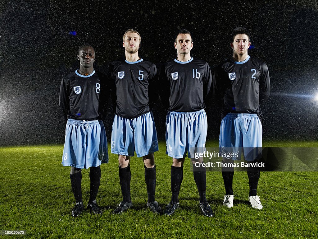 Soccer teammates standing on field in rainstorm