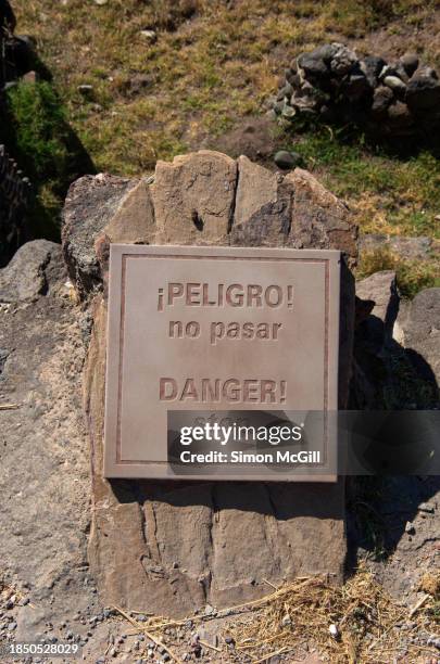 bilingual sign stating '¡peligro! no pasar/danger! stop' on a rock at tula archaeological site, tula, hidalgo, mexico - peligro stock pictures, royalty-free photos & images