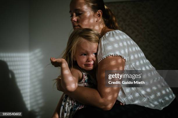mother holding her crying daughter at home. - larme photos et images de collection