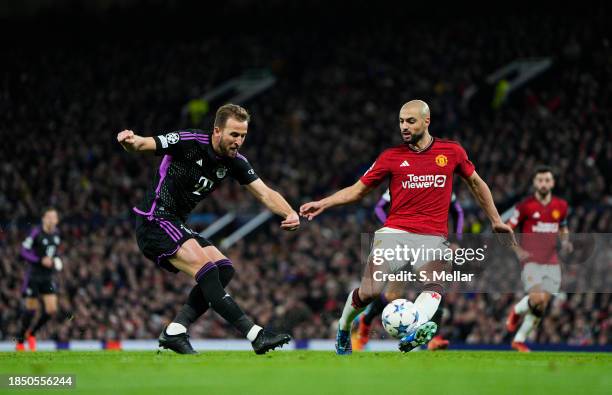 Harry Kane of Bayern Munich takes a shot whilst under pressure from Sofyan Amrabat of Manchester United during the UEFA Champions League match...