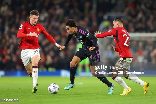 Jamal Musiala of FC Bayern München beats Antony and Scott McTominay of Manchester United during the UEFA Champions League match between Manchester...