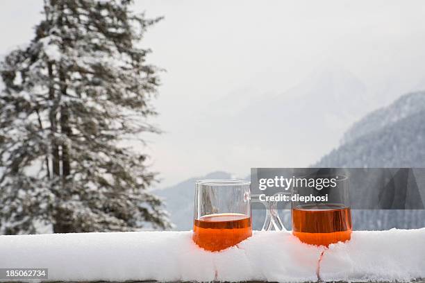 two glasses of drink sit on a snow covered ledge  - après ski stockfoto's en -beelden