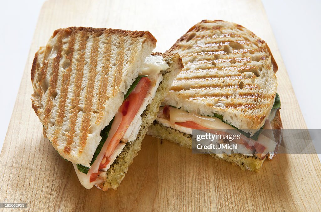 Panini with Chicken and Pesto on a Wooden Cutting Board.