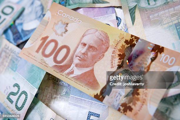 pile of canadian bills with one hundred dollars on top - canada stock pictures, royalty-free photos & images