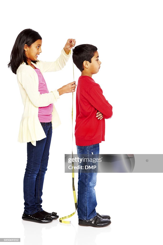 Girl measuring height of her young brother
