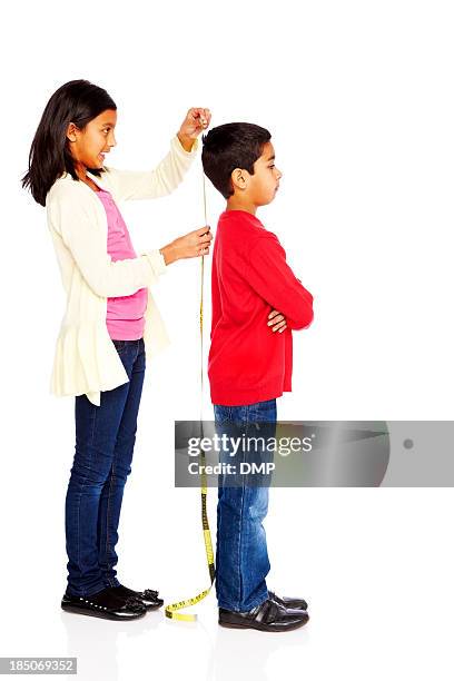 girl measuring height of her young brother - lang lichaamslengte stockfoto's en -beelden