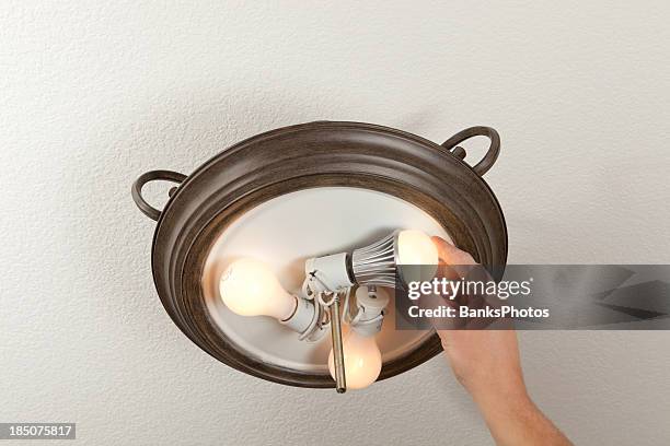 hand installing led light bulb into a ceiling fixture - installing ceiling light fixture stock pictures, royalty-free photos & images
