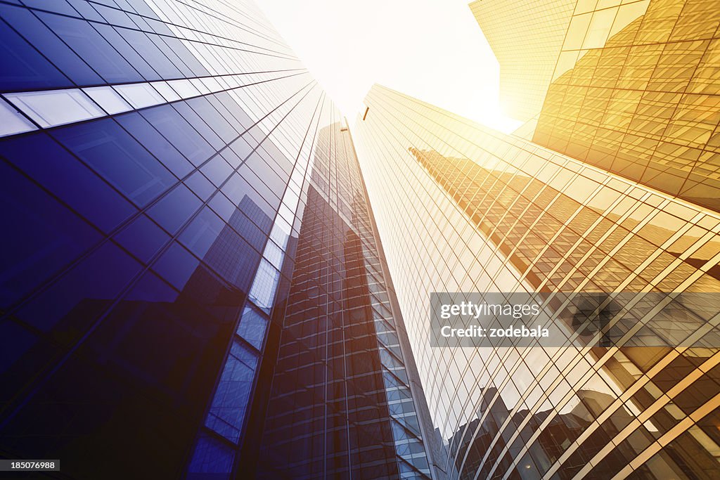 Looking up at tall buildings with sun shining down