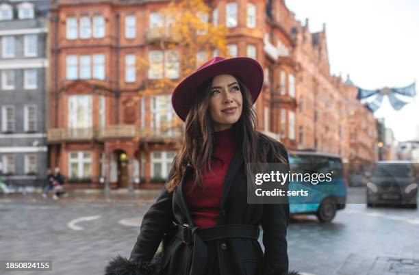 portrait of a stylish and beautiful urban young woman wearing a red hat in london's iconic streets on an cold autumn day - sloane square stock pictures, royalty-free photos & images