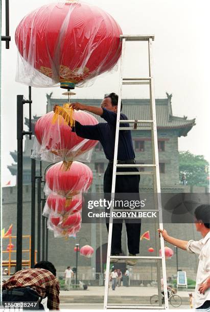 Workers hang red lanterns at the pathway to the south gate of Xian's ancient city wall 24 June in preparation for the welcoming ceremony for US...