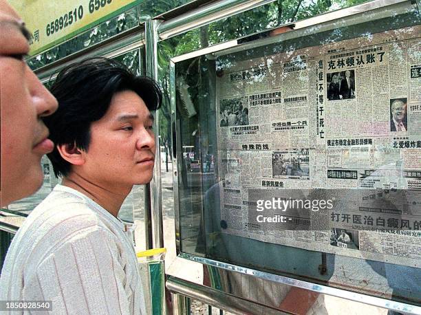 People read newspapers on a bulletin board in Beijing 19 August about US President Bill Clinton's televised speech to explain his affair with a White...