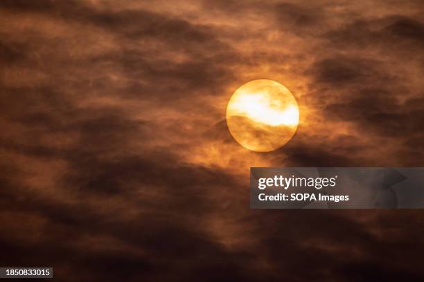 The sun rises while dark clouds loom in the sky on a cold winter day in Srinagar.