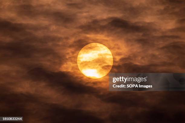 The sun rises while dark clouds loom in the sky on a cold winter day in Srinagar.