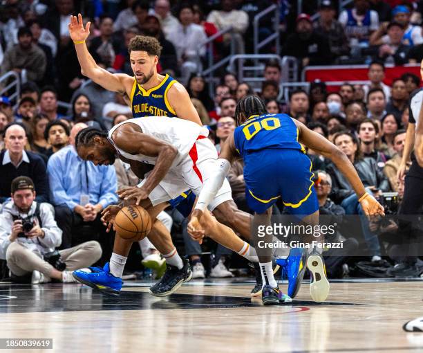 Clippers forward Kawhi Leonard dribbles through a double-team of Golden State Warriors guard Klay Thompson and Golden State Warriors forward Jonathan...