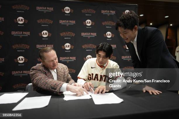 Jung Hoo Lee of the San Francisco Giants signs his contract with agents Scott Boras and Jeong Moon Lee after a press conference to introduce his...