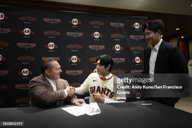 Jung Hoo Lee of the San Francisco Giants signs his contract with agents Scott Boras and Jeong Moon Lee after a press conference to introduce his...