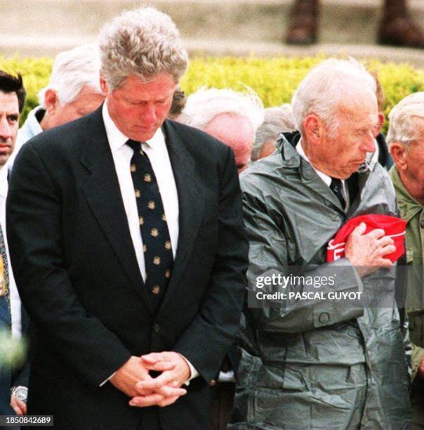 President Bill Clinton bows his head during a moment of silence as he stands with US veterans of the 06 June 1944 D-Day landings during a...