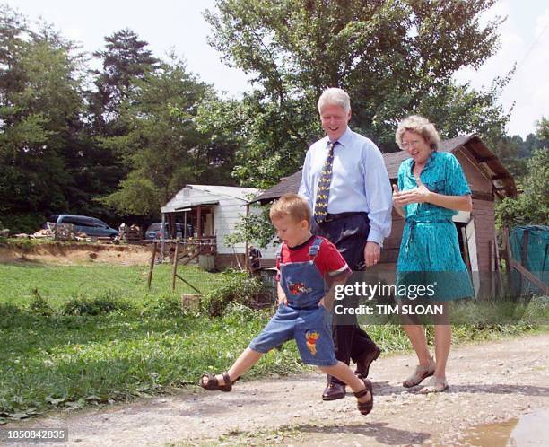 President Bill Clinton walks with Jean Collett as Shane Harrison, age 4, jumps down a road 05 July in the rural Whispering Pines neighborhood of...
