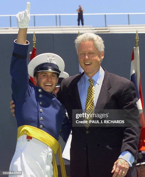 Robert Wayne Patrick Wolfe acknowledges the crowd with US President Bill Clinton at The US Air Force Academy's Falcon Field as the final graduate of...