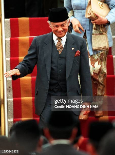 Indonesian President B. J. Habibie smiles as he descends the aircraft steps on his arrival at Hanoi's Noi Bai International Airport 14 December....