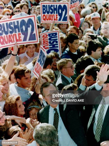 President George Bush waves to cheering students during a rally at Missouri Southern State College 11 September, 1992 in Joplin, Missouri. Bush later...
