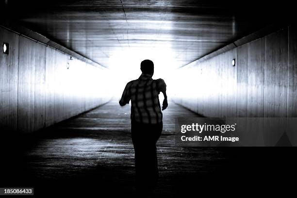 balck and white image of man's silhouette running - man escaping stock pictures, royalty-free photos & images