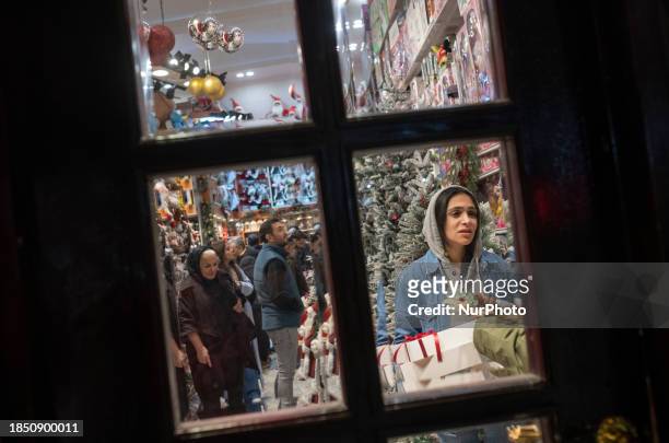 An Iranian-Christian woman is standing at a shop decorated for Christmas shopping in downtown Tehran, Iran, on December 15, 2023. While...