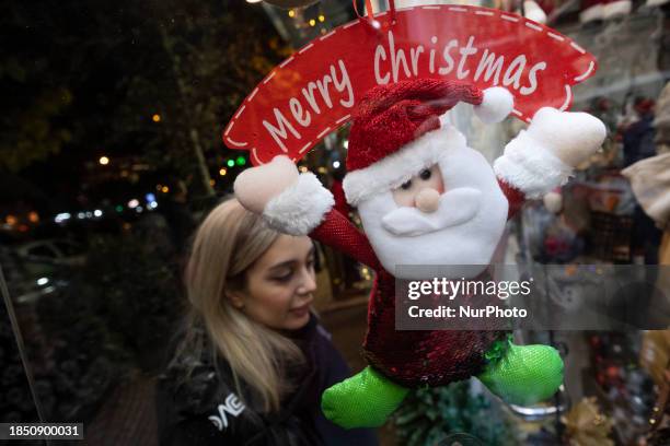 An Iranian-Christian woman is standing in front of a shop decorated for Christmas shopping in downtown Tehran, Iran, on December 15, 2023. While...