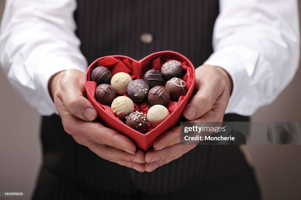 Man giving a heart shaped chocolate praline box