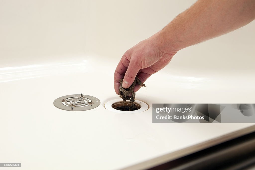 Plumber Removing Hair Clog From Shower Drain High-Res Stock Photo