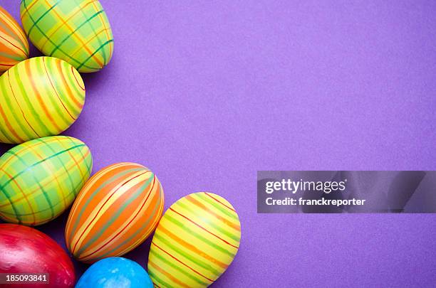 colored painted easter egg on purple background - easter background stock pictures, royalty-free photos & images