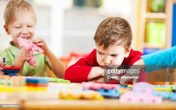 wütende kleine junge blick auf puzzles. - children playing school stock-fotos und bilder