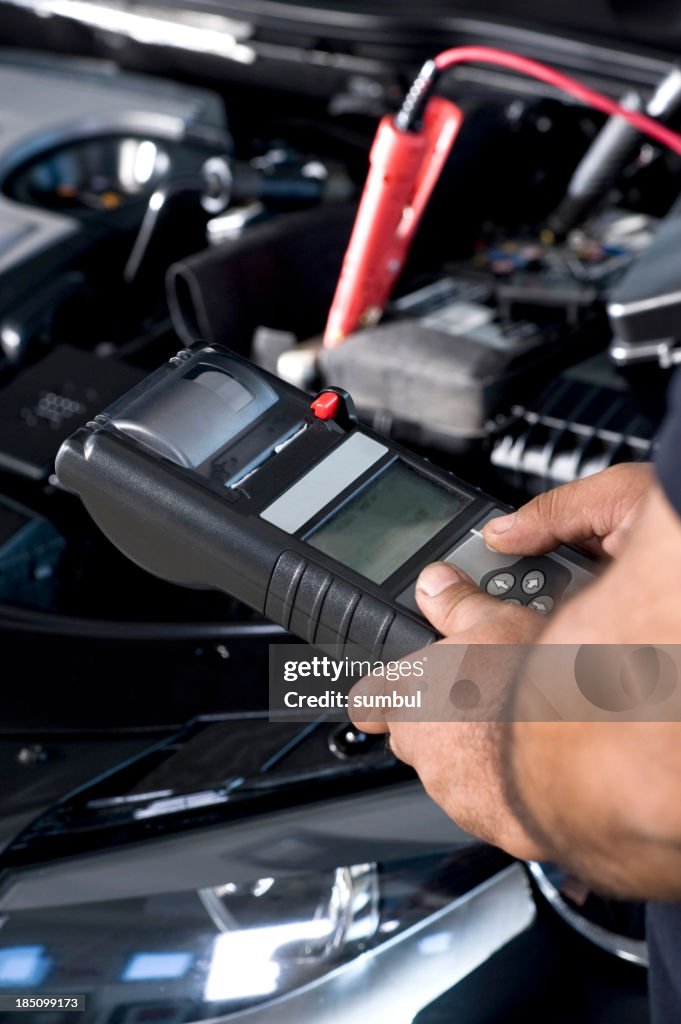 Auto mechanic checking car battery