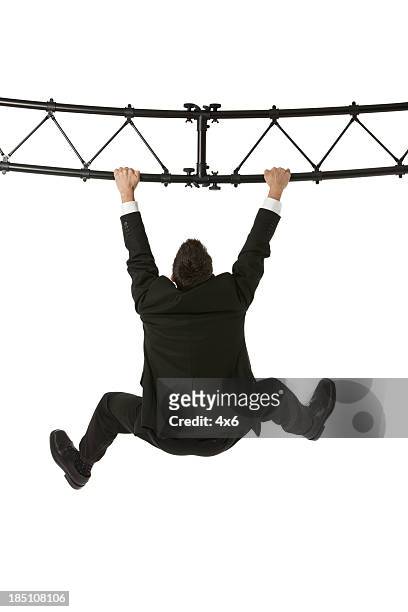businessman hanging from a metal structure - suits hanging stock pictures, royalty-free photos & images