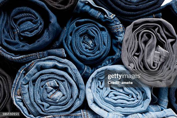gerollte denim-jeans - pile of clothes stock-fotos und bilder