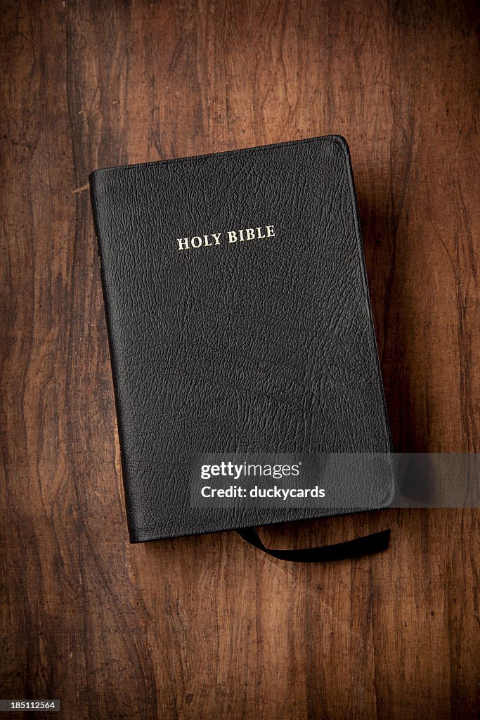 Holy Bible in Black Leather on Wood Background