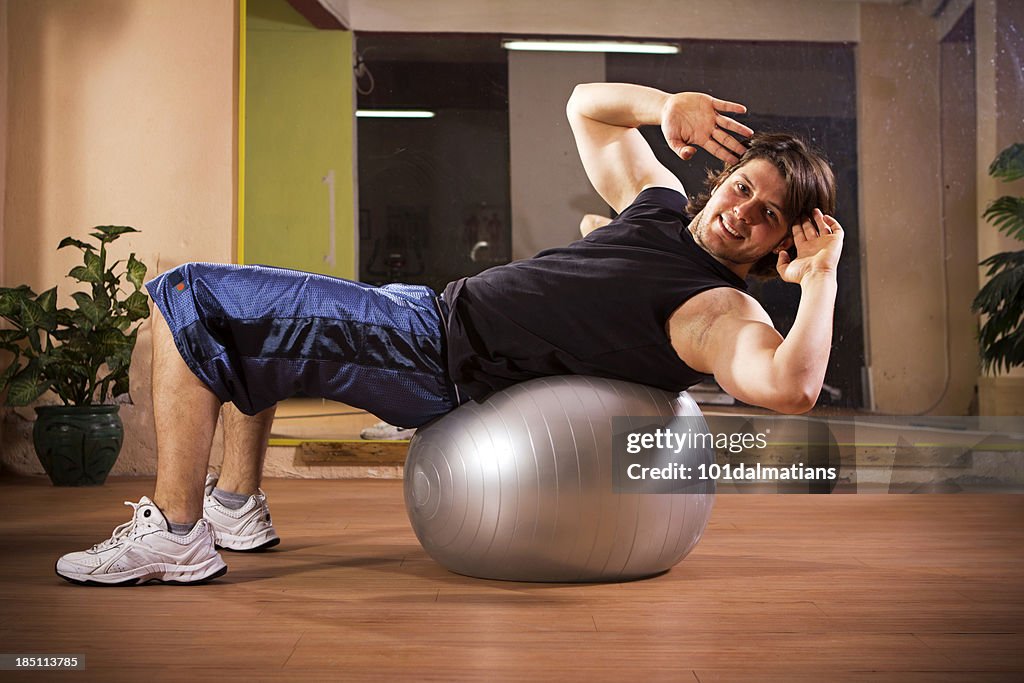 Sportliche junge Mann Training auf pilates-ball