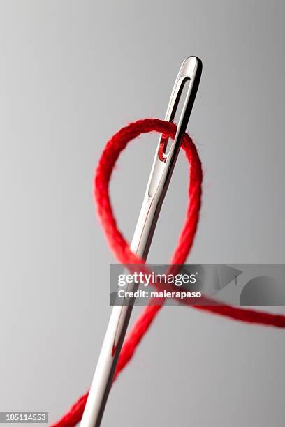 thread through the needle eye - rode draad stockfoto's en -beelden