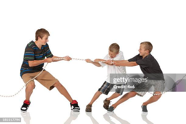 three boys playing tug-of-war - pulling stock pictures, royalty-free photos & images