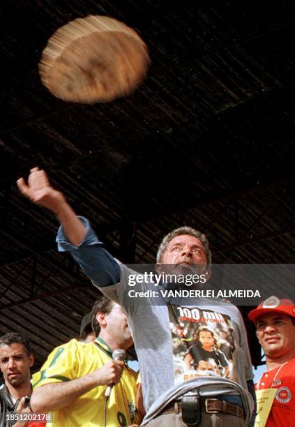 Honorary president of the Workers Party Luis Inacio Lula da Silva throws a pizza to the crowd of thousands of supporters 26 August during a protest...