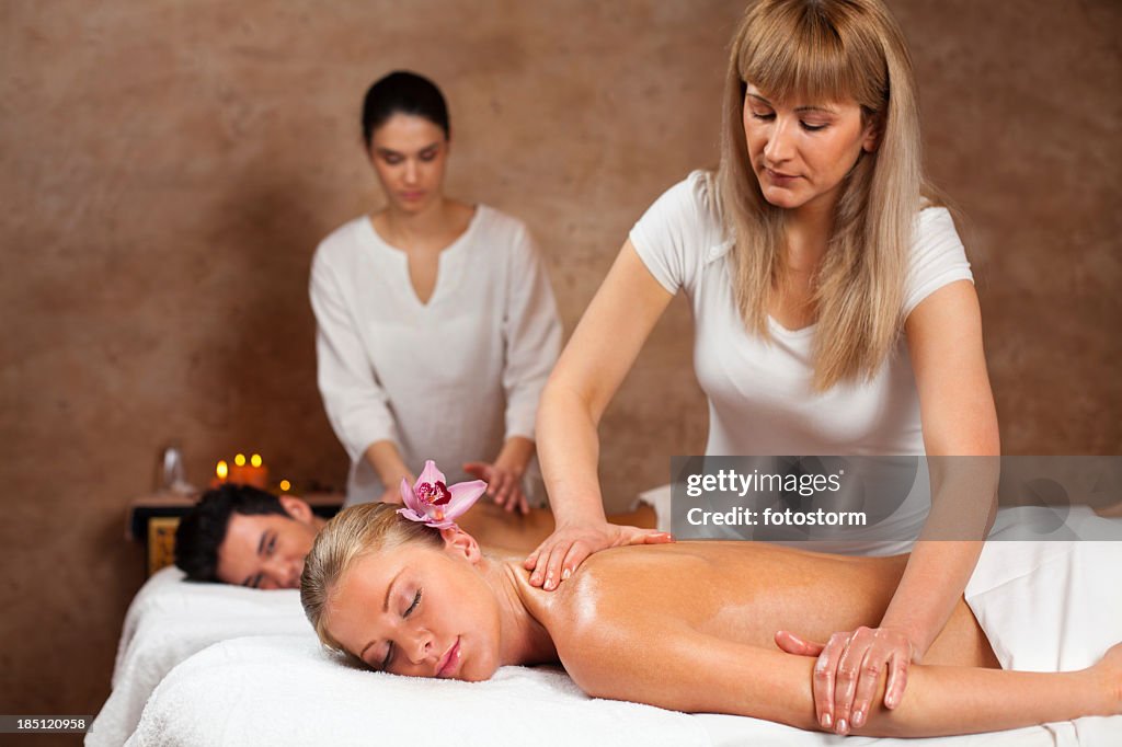 Therapists giving massage to a couple at health spa