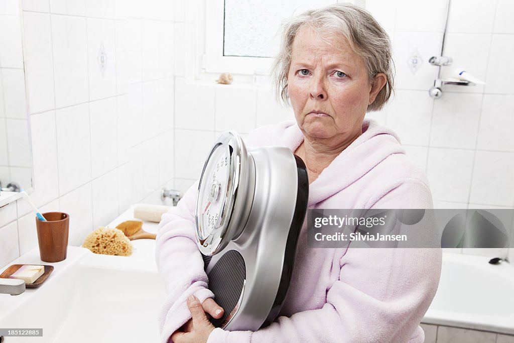Senior woman overweight scale bathroom unhappiness