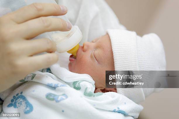 mother bottle feeding her premature baby in the hospital nursery - premature baby stock pictures, royalty-free photos & images