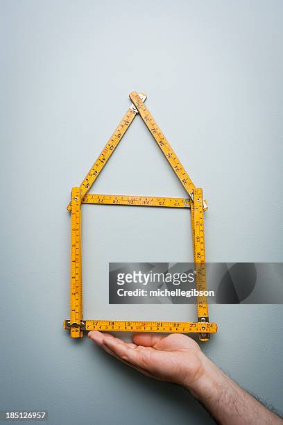 man shows a folding ruler in the shape of a home - house rules stock pictures, royalty-free photos & images