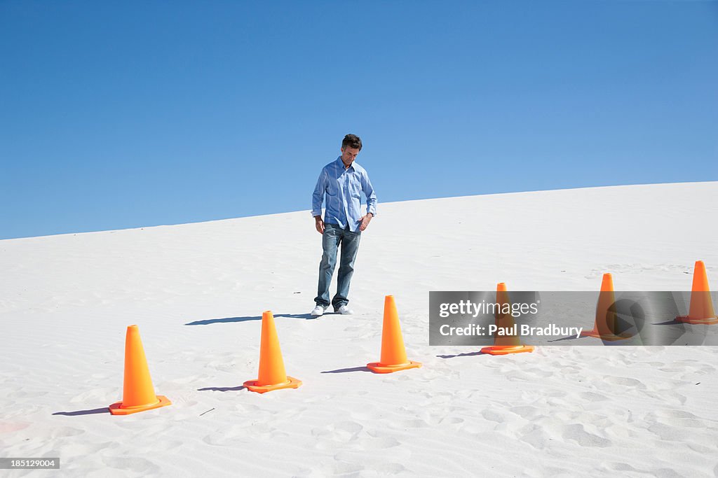 A man with traffic cones in the middle of desert