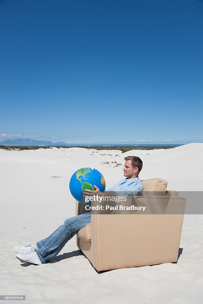 A man sitting on chair holding a globe