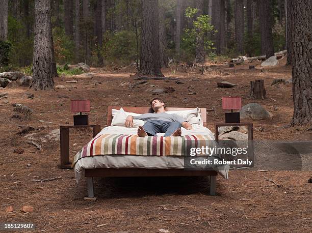 a man sleeping in a bed outdoors in the woods - ohne zusammenhang stock-fotos und bilder
