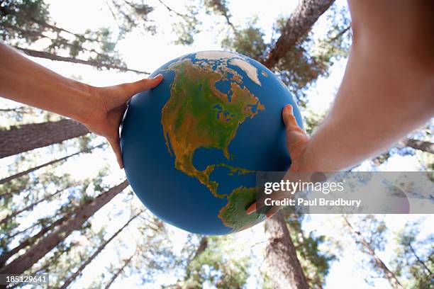 hands holding a globe - people holding hands around globe stock-fotos und bilder