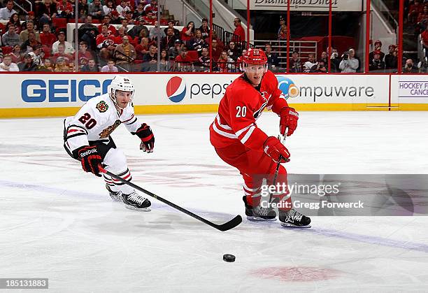 Riley Nash of the Carolina Hurricanes backhands the puck away from Brandon Saad of the Chicago Blackhawks during their NHL game at PNC Arena on...